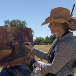 Woman painting outdoors in a hat