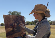 Woman painting outdoors in a hat