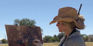 Woman painting outdoors in a hat