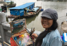 Plein air artist Hai-Ou Hou painting outside in China next to a river.