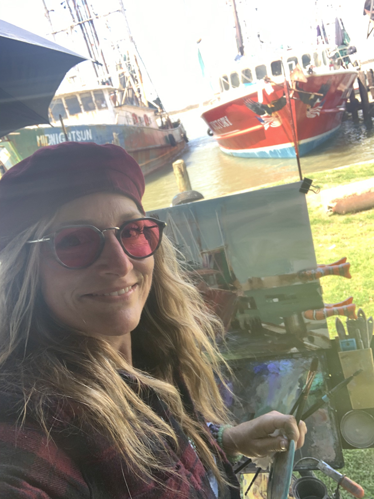 Selfie of woman creating a small painting of a boat from life