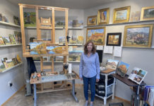 Female artist in her studio with easel and paintings on the walls