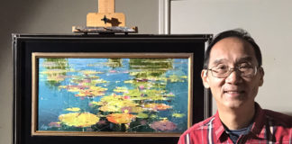artist posing with his most recent painting propped on an easel