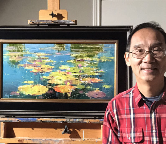 artist posing with his most recent painting propped on an easel