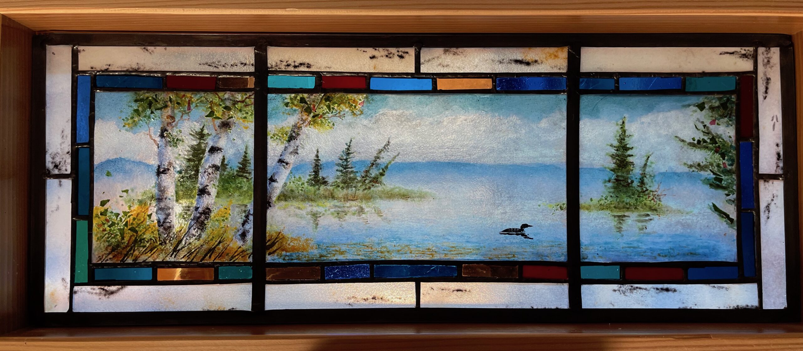 A glasswork piece titled "Transom Birches & Lake" by Robert Stump