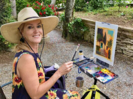 artist posing for a picture while painting at the easel outside