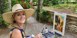 artist posing for a picture while painting at the easel outside