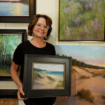 Kathleen posing with her paintings in her studio