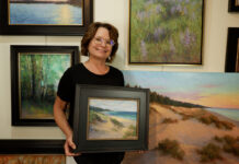 Kathleen posing with her paintings in her studio