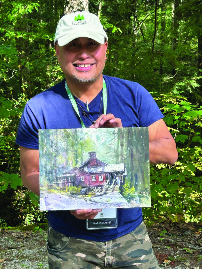 Plein air watercolor artist Richie Vios holding a painting